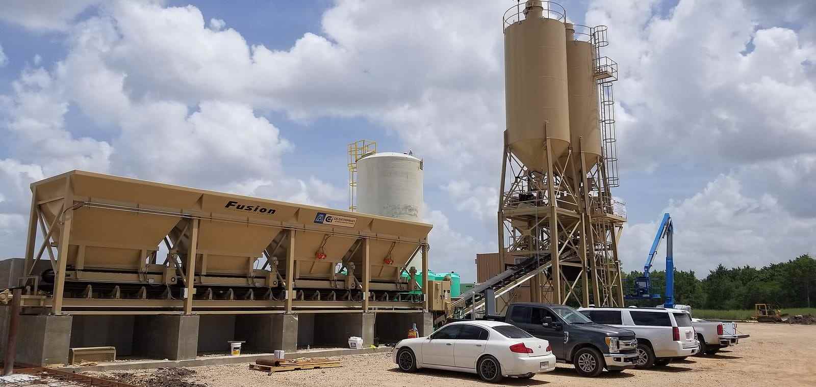 Silos and a conveyor at a concrete batching plant under a clear sky